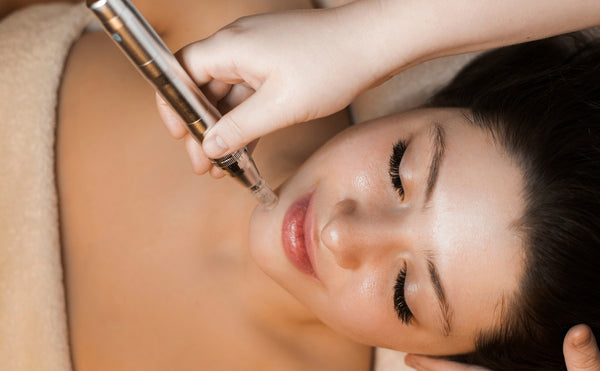 close-up of a woman lying on a treatment bed receiving a microneedling treatment for her skin performed by an aesthetic professional