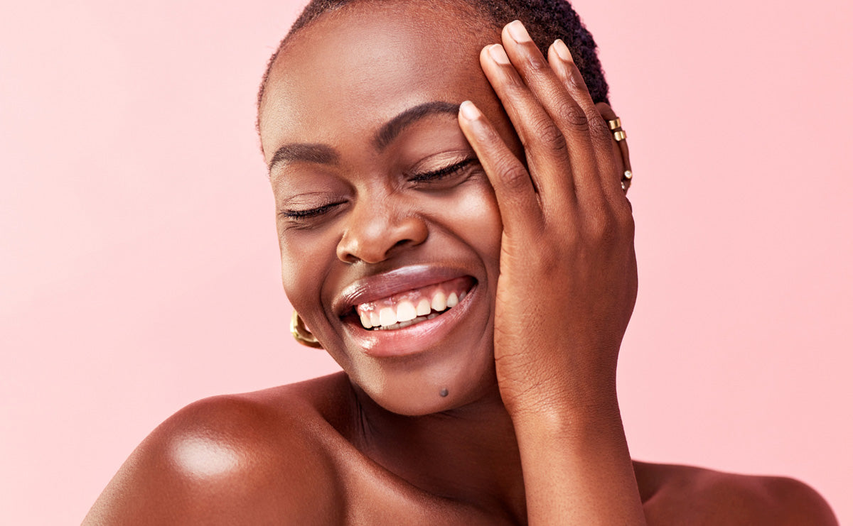 woman with clear skin smiling and touching her face