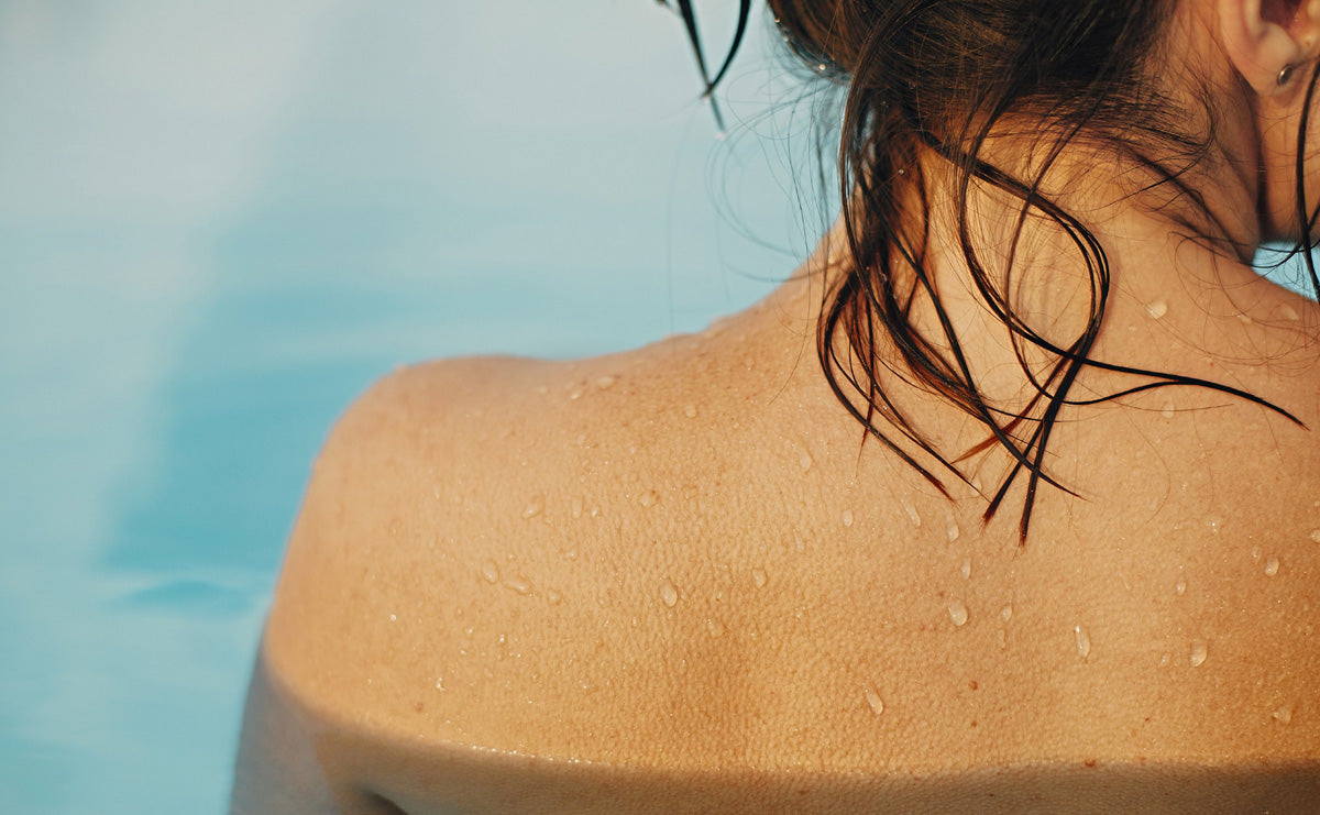 close-up shot of a woman from backside in a swimming pool with sun rays shining down, highlighting the sunburn healing properties of RescueMD