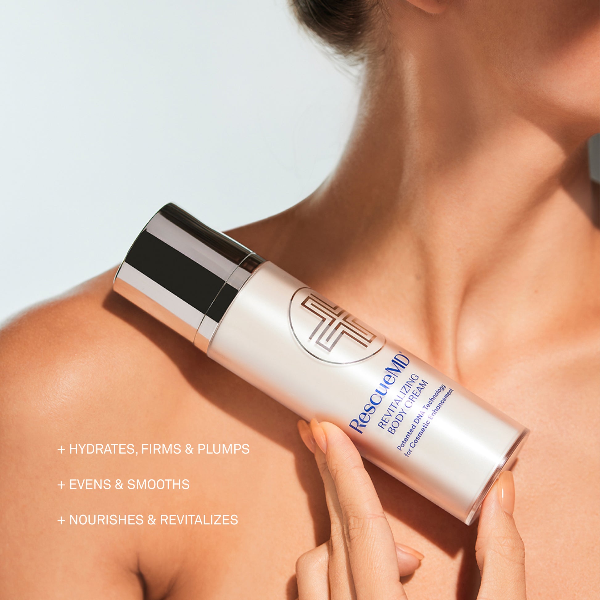 Hand holding a RescueMD Revitalizing Body Cream bottle on a light background