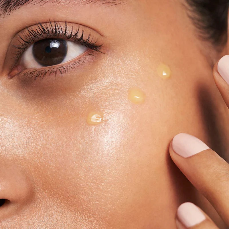 Close-up of a woman applying RescueMD DNA Repair Complex serum to her cheek for scar treatment and skin recovery.